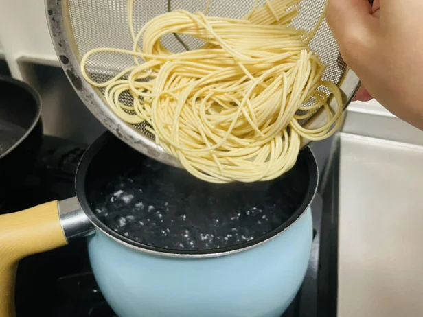 沸騰したお湯に塩を入れ、水につけた麺を入れる（▶次へ）