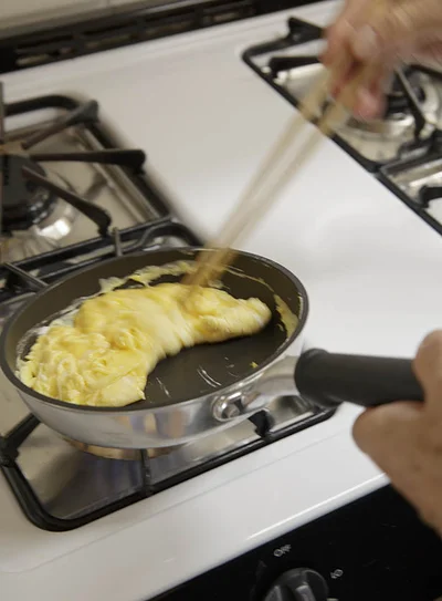 フライパンを奥に傾けて、卵の手前1/3を折ります。