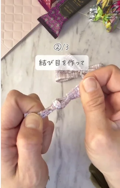 真ん中に結び目を作る▶じゃばら折りにしたリボンの…（⇒次へ）