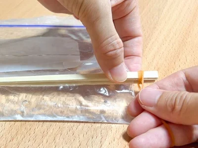 割りばしの両端を輪ゴムで固定する（▶次へ） 
