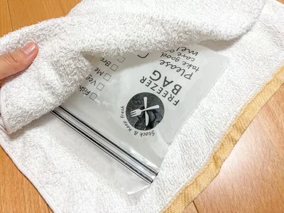 凍ったジップ付き保存袋をタオルで包む（▶次へ） 