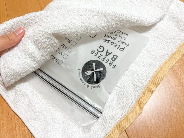 凍ったジップ付き保存袋をタオルで包む(▶次へ)