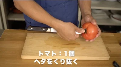 トマトのヘタのところに、包丁を少し斜めに向けて刺す