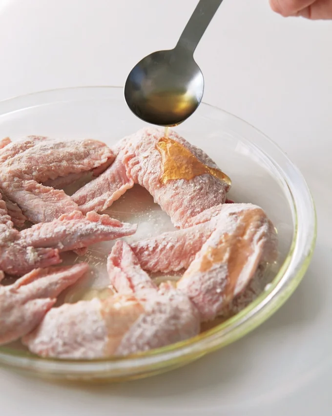 皮目を上にして並べ、ごま油大さじ1を全体にかける。「レンジ手羽先揚げ名古屋風」