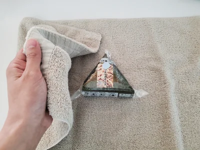タオルでおにぎりを優しく包みます（▶次へ）