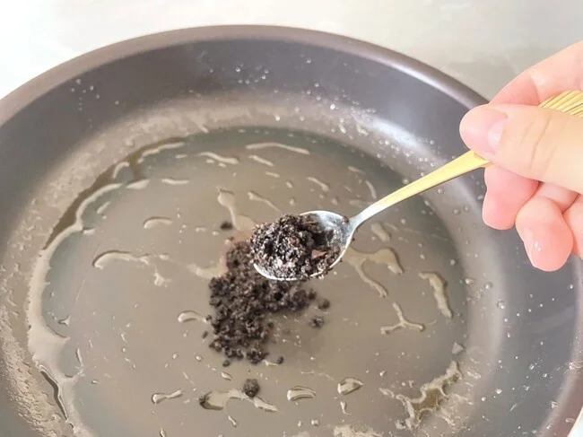 コーヒーかすを、粗熱が取れたフライパンに入れる(▶次へ)