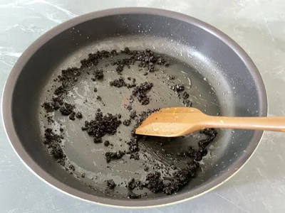 ヘラでコーヒーかすをフライパン全体に広げる（▶次へ）