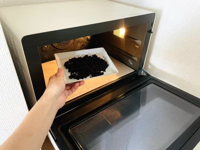 電子レンジで加熱して、コーヒーかすの水分を飛ばす（▶次へ）