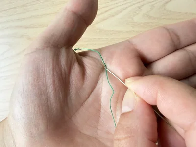 糸に針穴を強く押し当てて…（▶次へ）