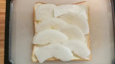 薄くバターを塗った食パンに、梨の薄切りを乗せていく。
