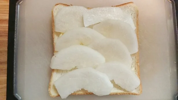 薄くバターを塗った食パンに、梨の薄切りを乗せていく。