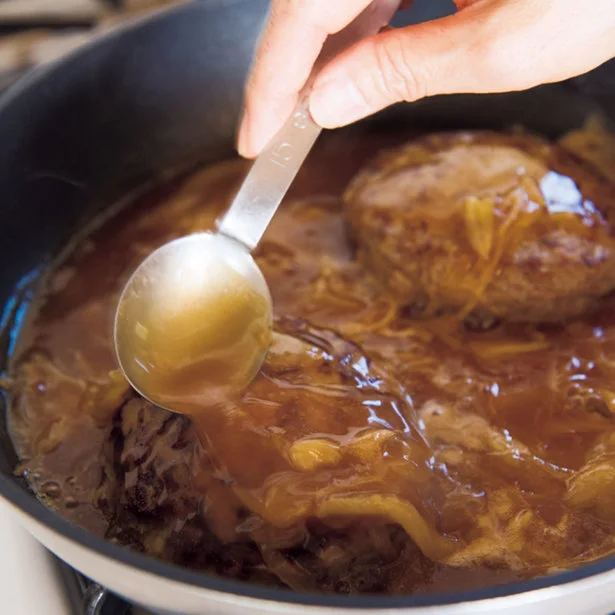 ハンバーグをおおうようにソースをかけて味をなじませる 