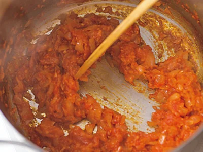 カレーのトマトは水分をとばすのがおいしく作るポイント。木べらで混ぜながらこのくらいまでよく炒めて。