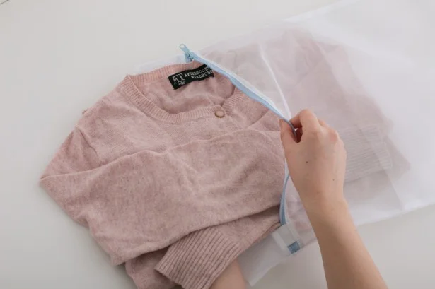 カーディガンなどは形崩れしないようにボタンやファスナーを留めます。衿元や袖口などの汚れやすい部分が外側にくるように畳んで洗濯ネットに。