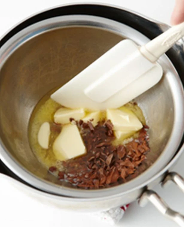 【写真を見る】細かく刻んだチョコと粗く刻んだバターをボウルに入れ、湯せんしながら、耐熱性のへらで混ぜ溶かす