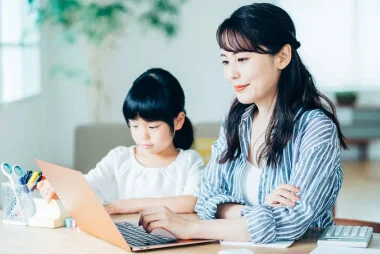 子どもと一緒にパソコンに向かう女性の画像