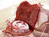 肉だねを広げたら、トマトを片側にのせる。ラップを使えば肉だねが扱いやすい。