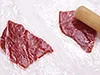 牛肉をラップではさんで、めん棒でたたく。薄くのばすことにより、火の通りも早くなり、肉がやわらかくなる。