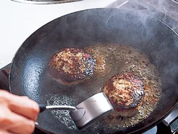ハンバーグの表面を焼き固めたら、ワインを回しかける。焼いている途中で、水分を与えることにより、かたく縮むのを防ぐ。