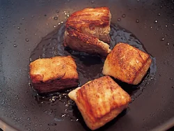 ゆでた豚肉をさらにこうばしく焼きつける。こんがりと焼けた部分が煮込んだときにうまみを増す。
