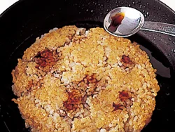 玄米ご飯の両面をフライパンでこんがり焼いたら、しょうゆをふってこうばしく仕上げる。