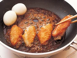 たれが煮立ったら揚げ焼きにした手羽先を入れる。小麦粉をまぶしてあるので、たれがよくからみ、ご飯が進む味に。ゆで卵も加えておかずらしく。