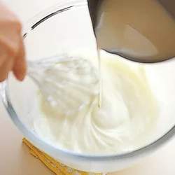 クリームチーズと砂糖を練ったら、練乳と牛乳などを加えたものを加える。泡立て器で混ぜながら、少しずつ加えると、混ざりやすい。