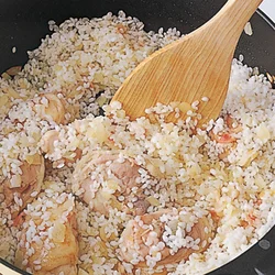 とり肉、ベーコン、玉ねぎ、米を順に加えて炒め、米にうまみをなじませる。