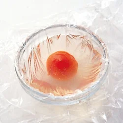 小さいボウルやおちょこにラップを大きめに敷き、寒天液を入れて甘く煮たトマトをのせる。