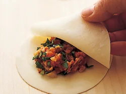 ２枚の餃子の皮で、あんをサンドするように円盤形に包み、縁を押さえて留める。