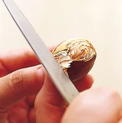 かたい鬼皮は、包丁の刃元で切り目を入れ、刃と親指で皮をはさんで持ち、はぎ取る。