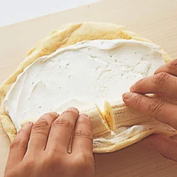 生クリームをぬってバナナをのせたら、手で生地を持ち上げて、手前からくるくると巻く。