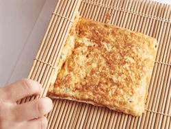 両面色よく焼いた卵焼きは、巻きすでしっかり巻く。巻きすがなければアルミホイルで巻いても。