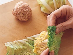白菜の葉はさっとゆでてやわらかくし、ひき肉だねを包む。最初に小さい葉で包み、さらに大きい葉で包む。