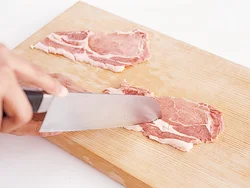 焼いたとき、縮んだり反り返るのを防ぐため、豚肉の脂身と赤身の境にある筋を切る。