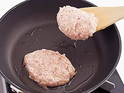 ハンバーグだねはやわらかいので、木べらですくって並べ入れ、フライパンの中で形を整える。