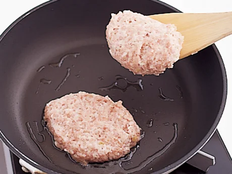 ハンバーグだねはやわらかいので、木べらですくって並べ入れ、フライパンの中で形を整える。