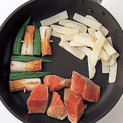 ３品の材料をフライパンにのせる。１品目、ちくわとオクラの串焼きを仕上げる