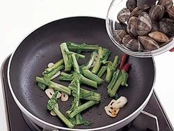 菜の花の茎はややかたいため、最初に炒める。あとで蒸し焼きにするため、油がまわるくらいでよい。
