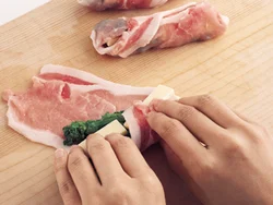 菜の花とチーズを豚肉に対して斜めに置いて、端を折り込むように巻くときれいに巻ける。チーズが豚肉からはみ出ていると油がはねやすいので注意。
