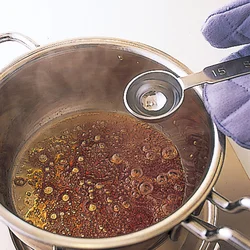 糖が茶色く色づいたら、熱湯を加えてのばす。はねるのでミトンを。
