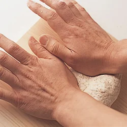 両手の親指のつけ根で生地を向こう側に押しつけては返し、体重をかけてこねる。