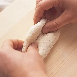 生地を三つ折りにしたら、上からしっかり押さえて平らにしてから、生地を巻き込んで棒状にする。