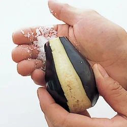 手に粗塩をつけて、しま目に皮をむいた水なすに、ぎゅっと握るようにもみ込む。実がくずれやすいので強く握りすぎない。