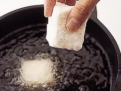 油がはねないように、豆腐にしっかり片栗粉をまぶし、軽くはたいて余分な粉を落としてから、油に入れる。