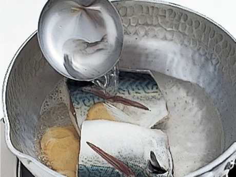 さばに煮汁をかけて表面に膜を作り、うまみを閉じ込める。