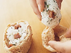 油揚げが破れないように裏返し、口を内側に１〜２cm折ってすし飯を詰める。油揚げの内側の口当たりが楽しめる。