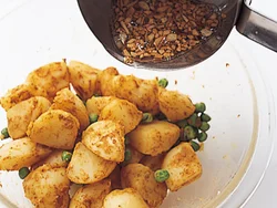 じゃがいもは熱いうちに、カレー粉、トマトケチャップ、塩でしっかりと味をつけ、あとからオイルをかけ風味をつける。にんにく、クミンシードを熱したオイルも、熱いうちにかけることでべたつかず、なじみやすくなる。