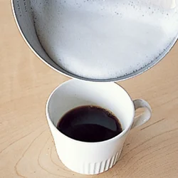 泡立て器でふんわり泡立てた牛乳を、濃いめのコーヒーに注ぐ。
