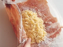 のばした豚肉にじゃがいもをのせたら、ラップごと豚肉を持ち上げてじゃがいもを包む。